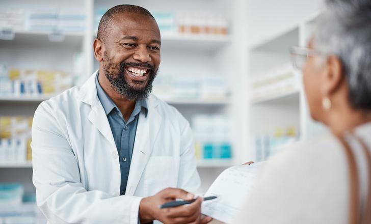 A pharmacist handing a patient medication.