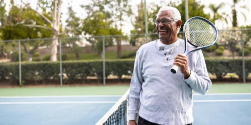 A man laughing on a tennis court.