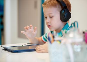 Boy using ipad and headphones for speech therapy
