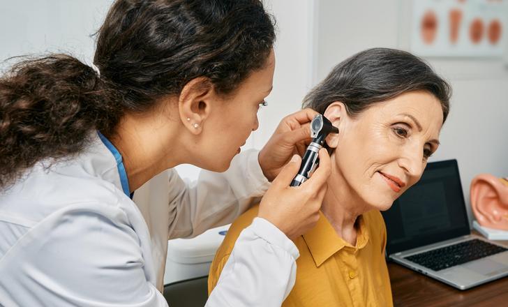 A lady getting a hearing check from an audiologist.